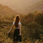 Frau steht auf einer Wiese und schaut in die Ferne