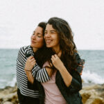 Freundinnen umarmen sich an einer Küste