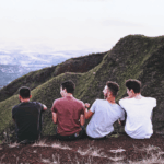 4 Männer sitzen nebeneinander auf einem Berg